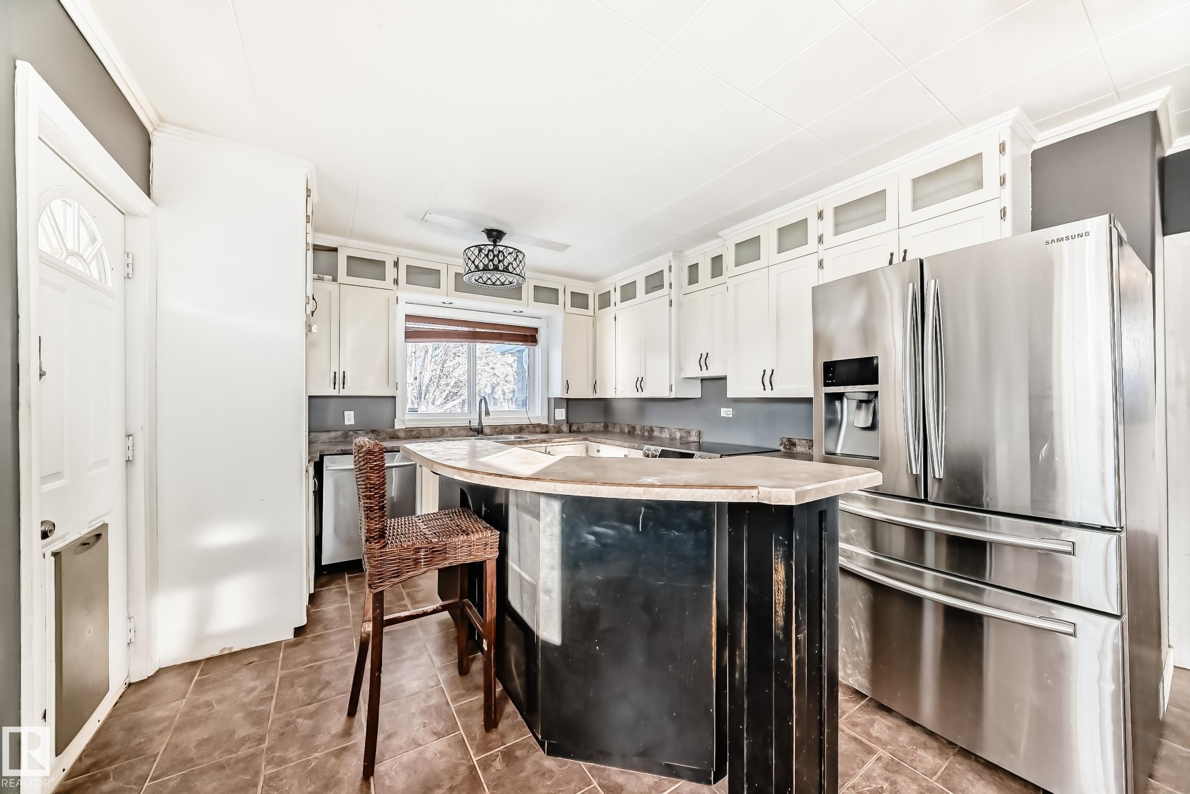 Kitchen with appliances with stainless steel finishes, white cabinets, light countertops, a kitchen bar, and glass insert cabinets - 10115 104, Westlock, AB - Indoor Photo Showing Kitchen