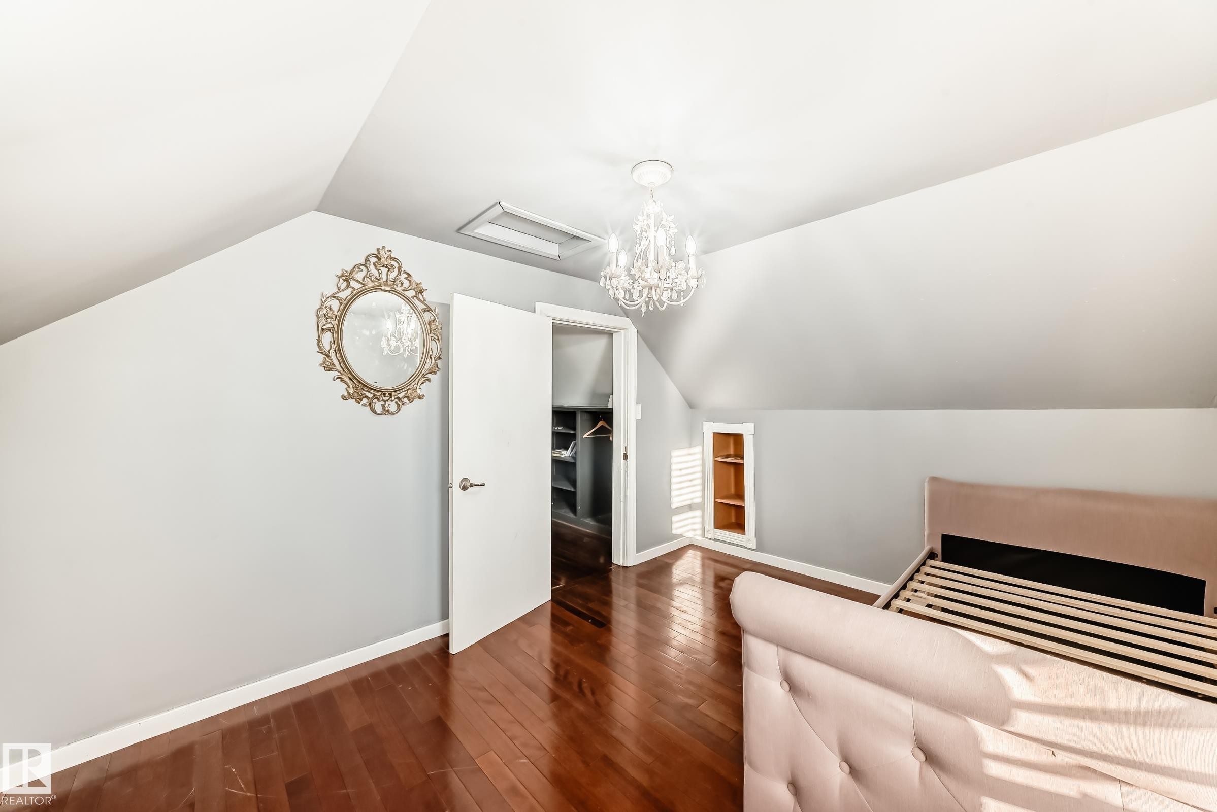 Unfurnished bedroom featuring lofted ceiling, dark wood-type flooring, a chandelier, and attic access - 10115 104, Westlock, AB - Indoor Photo Showing Other Room