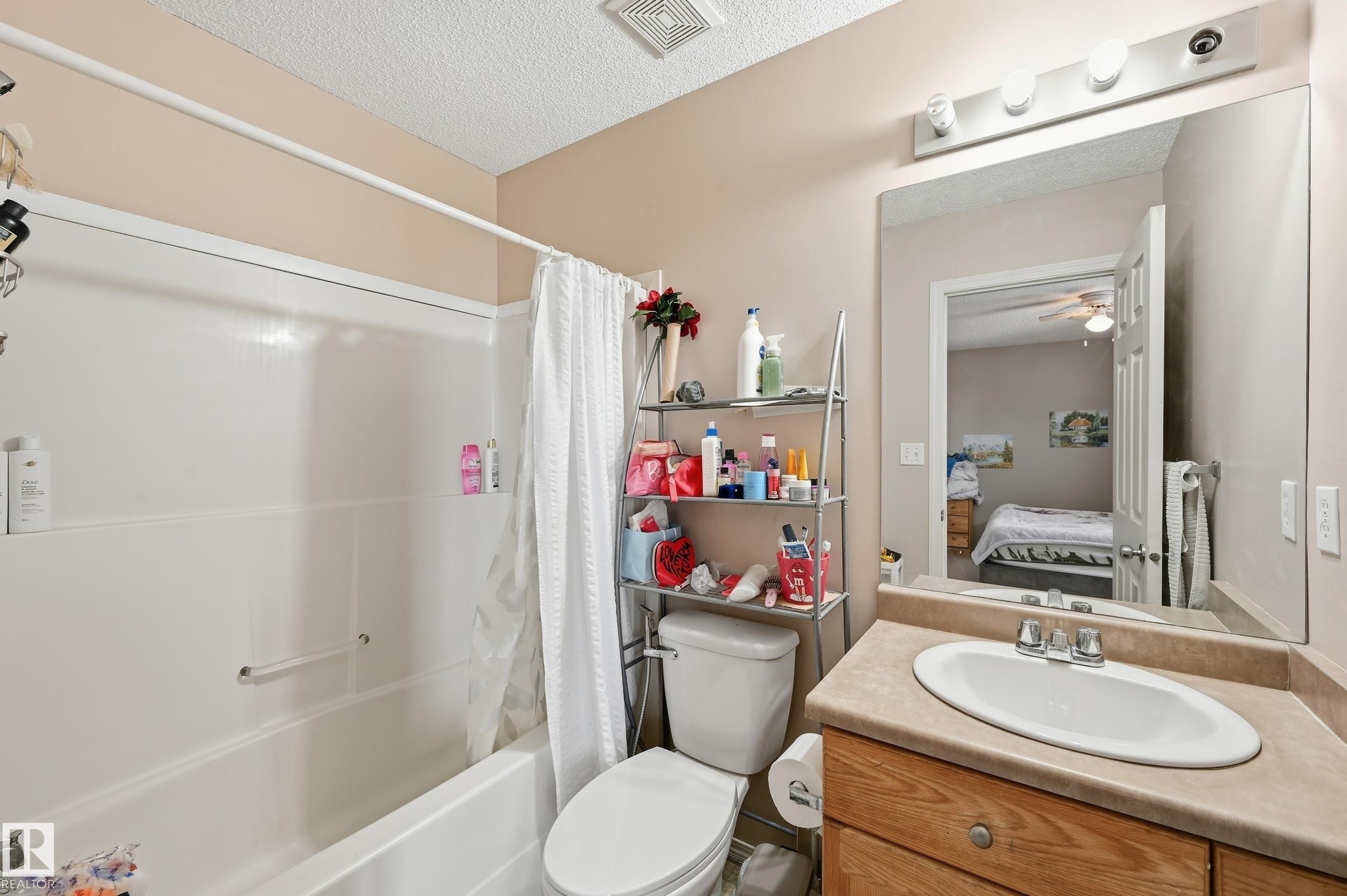 Full bathroom with vanity, shower / bathtub combination with curtain, a textured ceiling, ceiling fan, and connected bathroom - 3010 32 Avenue Nw, Edmonton, AB - Indoor Photo Showing Bathroom