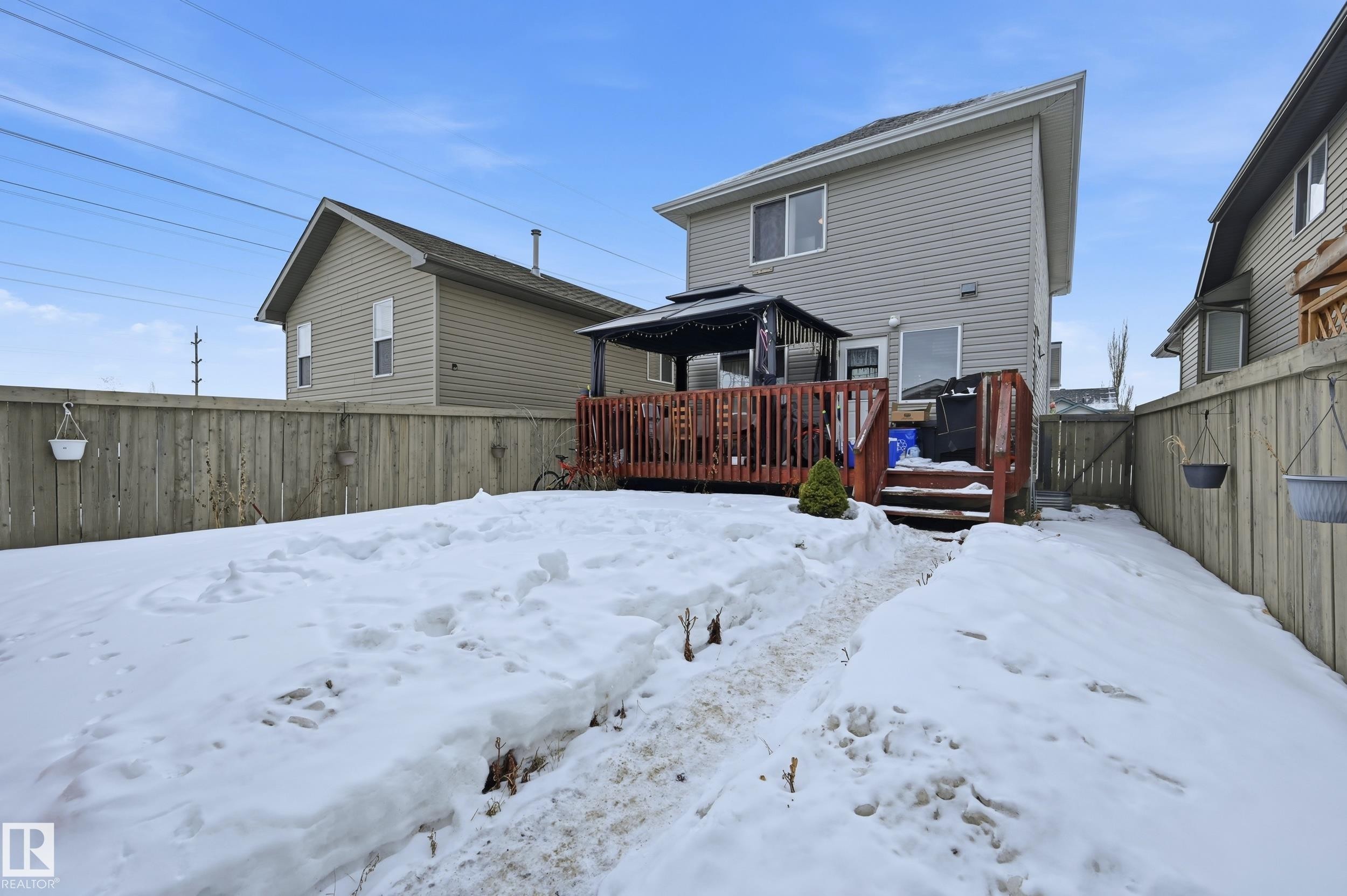 Snow covered house featuring a fenced backyard and a deck - 3010 32 Avenue Nw, Edmonton, AB - Outdoor With Deck Patio Veranda