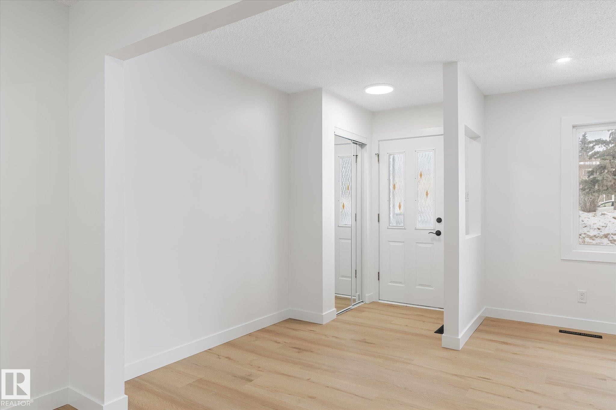 Foyer entrance with light wood finished floors and a textured ceiling - 5105 106A Street, Edmonton, AB - Indoor Photo Showing Other Room