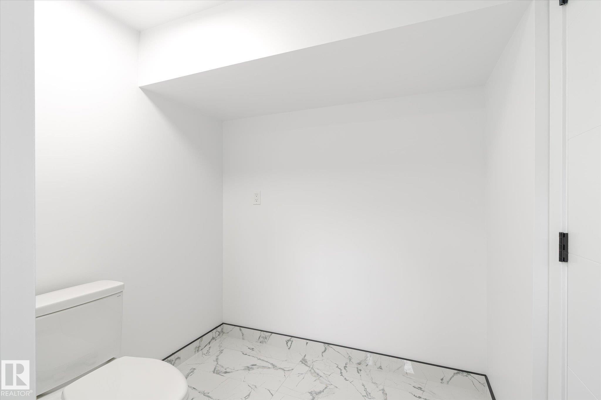 Half bathroom with toilet and marble finish flooring - 5105 106A Street, Edmonton, AB - Indoor Photo Showing Bathroom