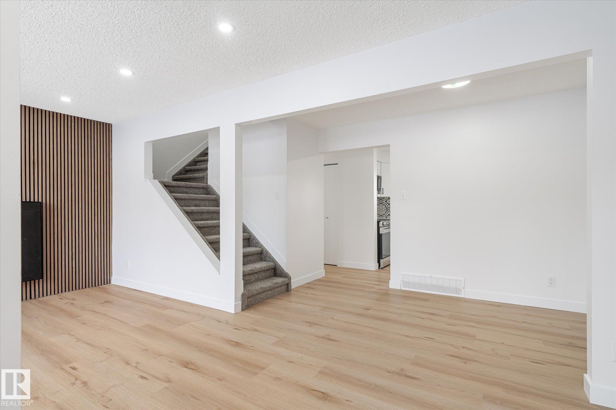 Basement featuring a textured ceiling, recessed lighting, stairs, light wood-style floors, and an accent wall - 5105 106A Street, Edmonton, AB - Indoor Photo Showing Other Room