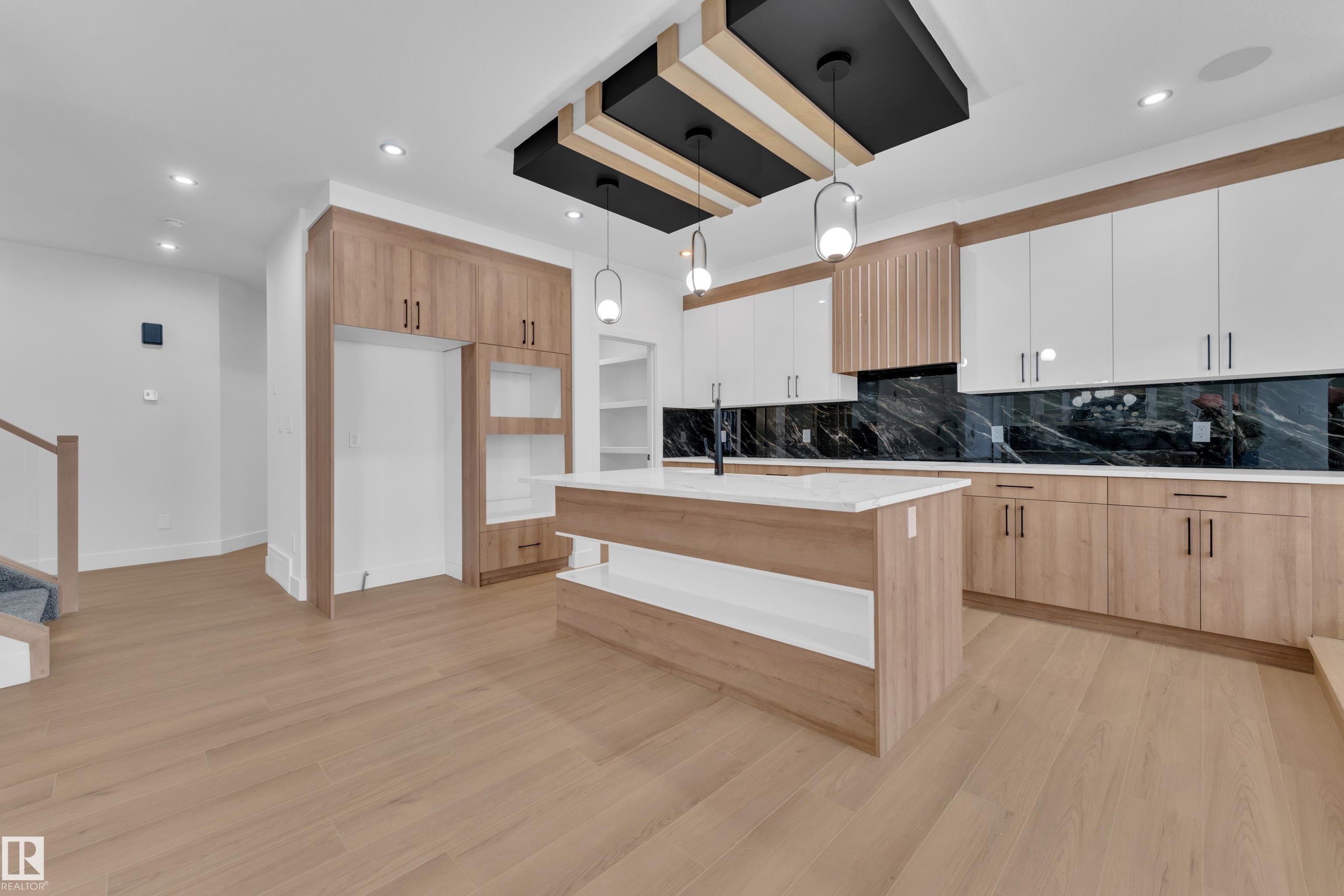 Kitchen with decorative light fixtures, tasteful backsplash, light wood-type flooring, dual tone cabinets, and a center island with sink - 733 Astoria Way, Devon, AB - Indoor Photo Showing Kitchen