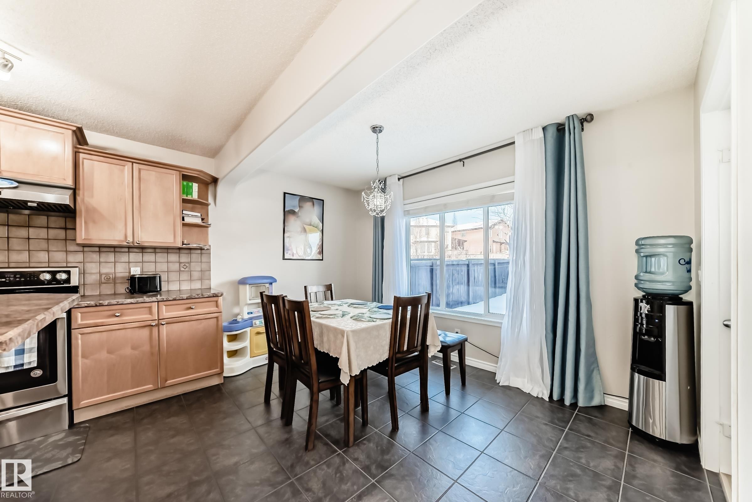 Dining room with dark tile patterned flooring and a chandelier - 5814 165 Avenue, Edmonton, AB - Indoor