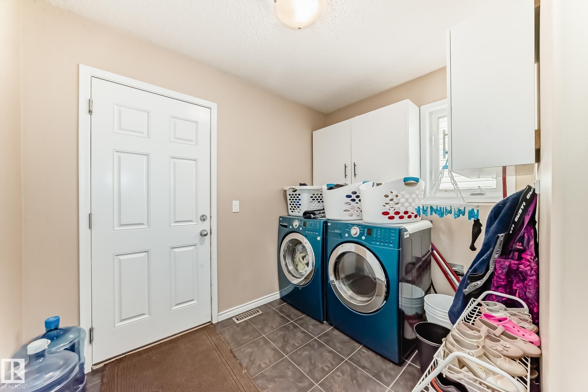 Laundry area with dark tile patterned floors, cabinet space, and washer and clothes dryer - 5814 165 Avenue, Edmonton, AB - Indoor