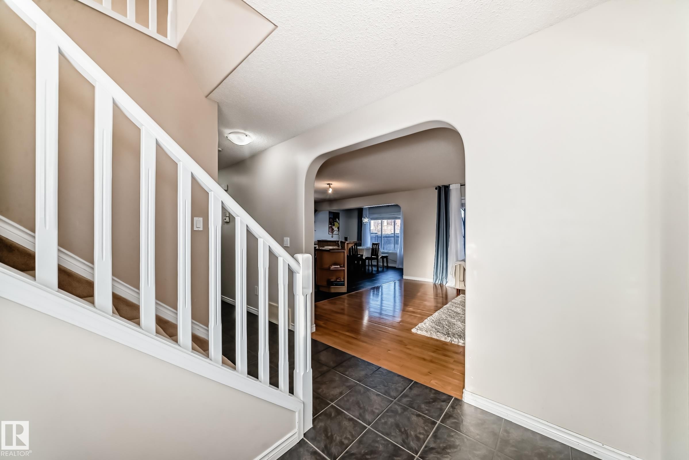 Entrance foyer with arched walkways, dark tile patterned flooring, and a textured ceiling - 5814 165 Avenue, Edmonton, AB - Indoor Photo Showing Other Room