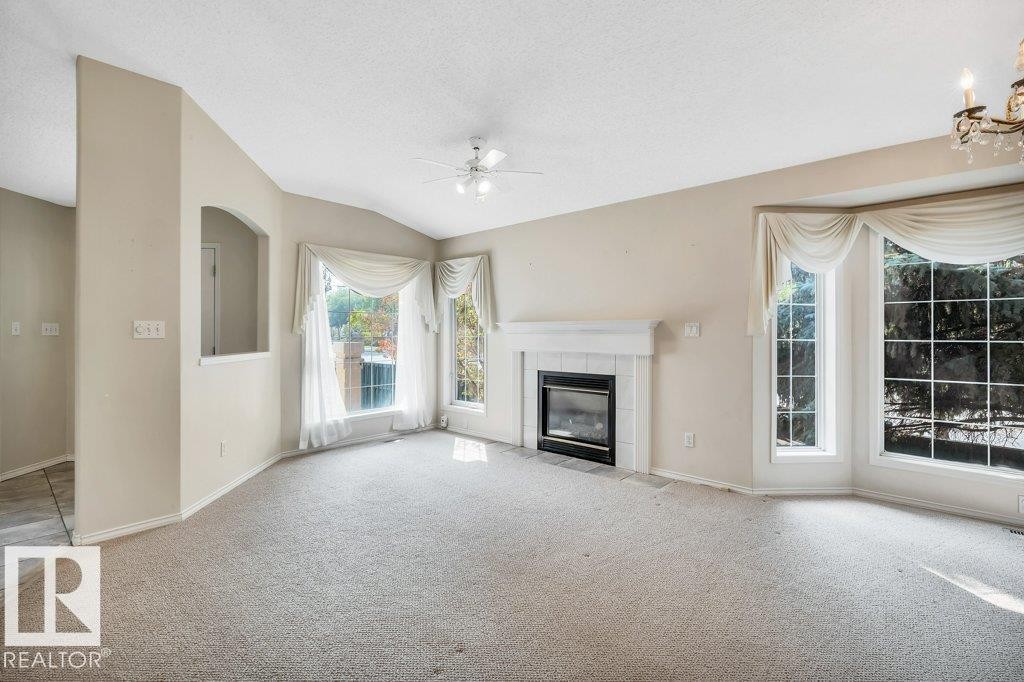 Unfurnished living room with carpet floors, a tile fireplace, and ceiling fan - 112 Haddow Close, Edmonton, AB - Indoor With Fireplace