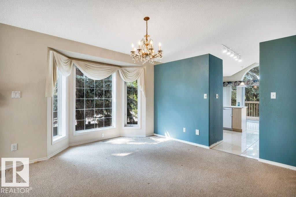 Unfurnished dining area featuring carpet, hanging lights, and a textured ceiling - 112 Haddow Close, Edmonton, AB - Indoor Photo Showing Other Room