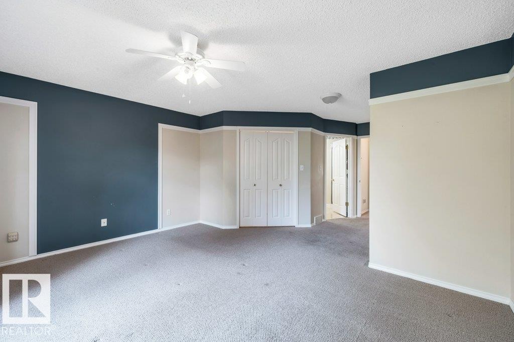 Unfurnished bedroom featuring a textured ceiling, carpet flooring, a closet, and a ceiling fan - 112 Haddow Close, Edmonton, AB - Indoor Photo Showing Other Room