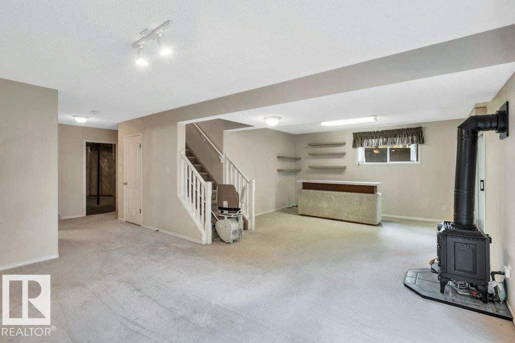 Basement featuring carpet floors, a wood stove, and a textured ceiling - 112 Haddow Close, Edmonton, AB - Indoor Photo Showing Basement