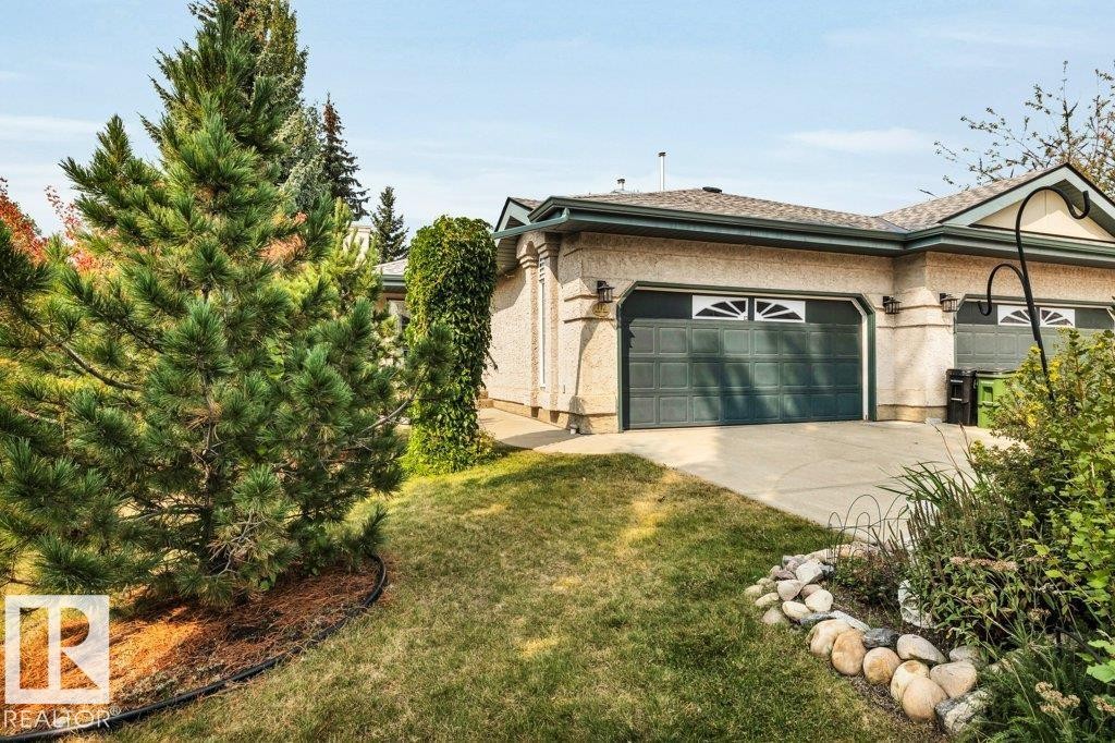 View of side of home featuring a yard, concrete driveway, and an attached garage - 112 Haddow Close, Edmonton, AB - Outdoor