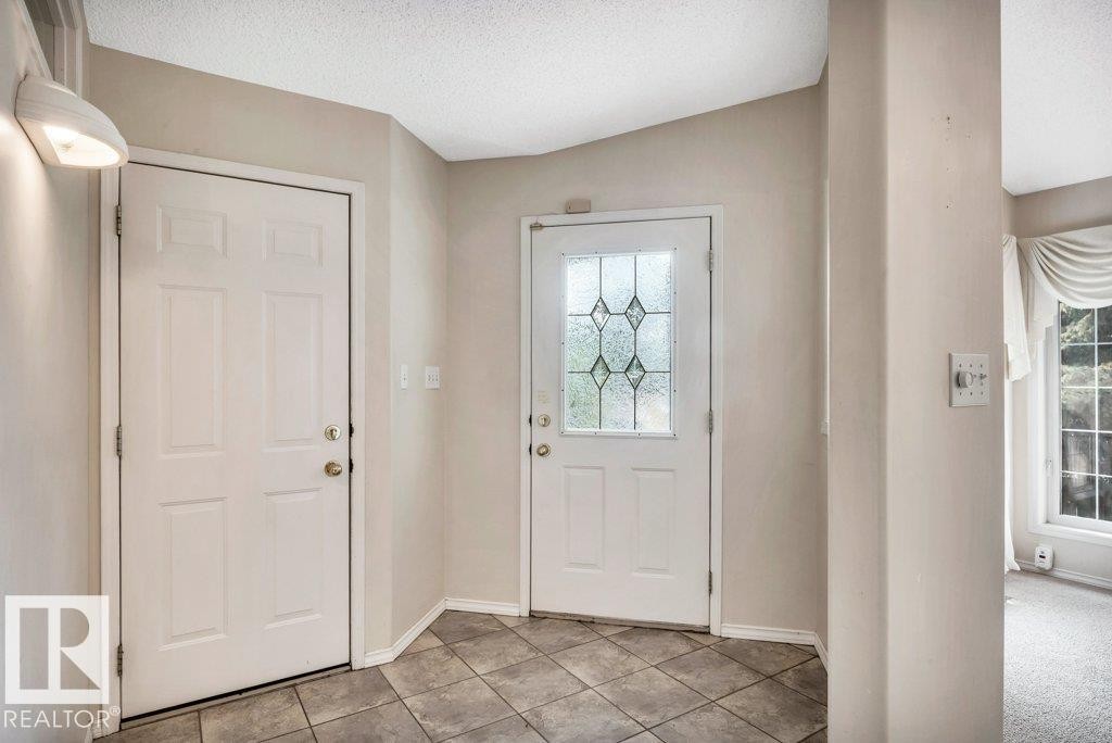 Tiled foyer entrance with a textured ceiling and baseboards - 112 Haddow Close, Edmonton, AB - Indoor Photo Showing Other Room