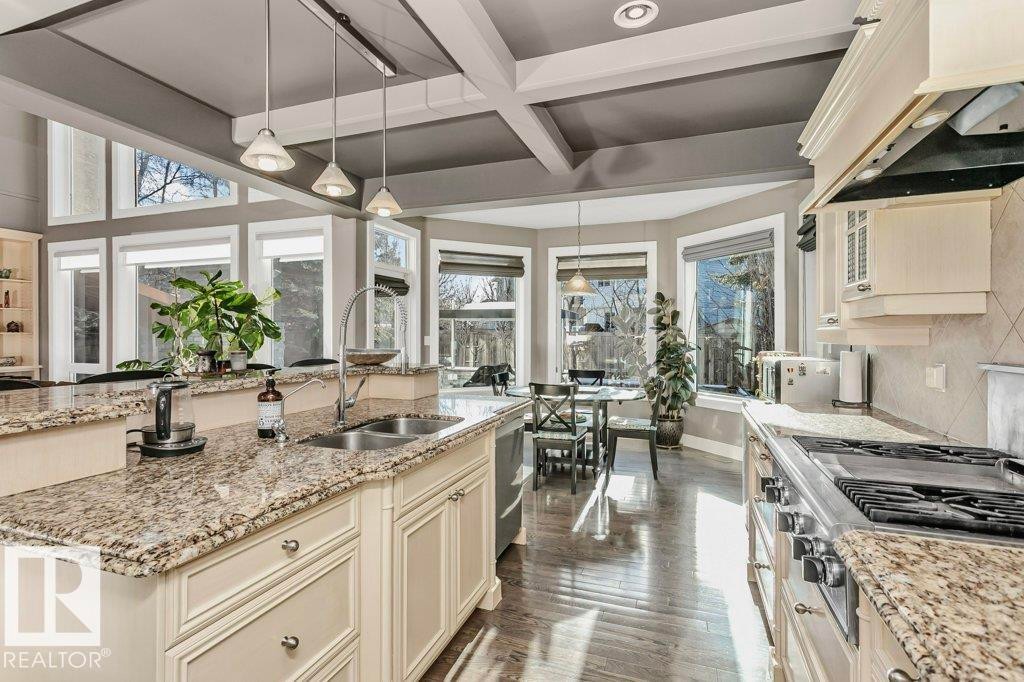 Kitchen featuring light stone counters, decorative light fixtures, stainless steel appliances, dark wood-style floors, and a kitchen island with sink - 1579 Hector Road, Edmonton, AB - Indoor Photo Showing Kitchen With Double Sink With Upgraded Kitchen