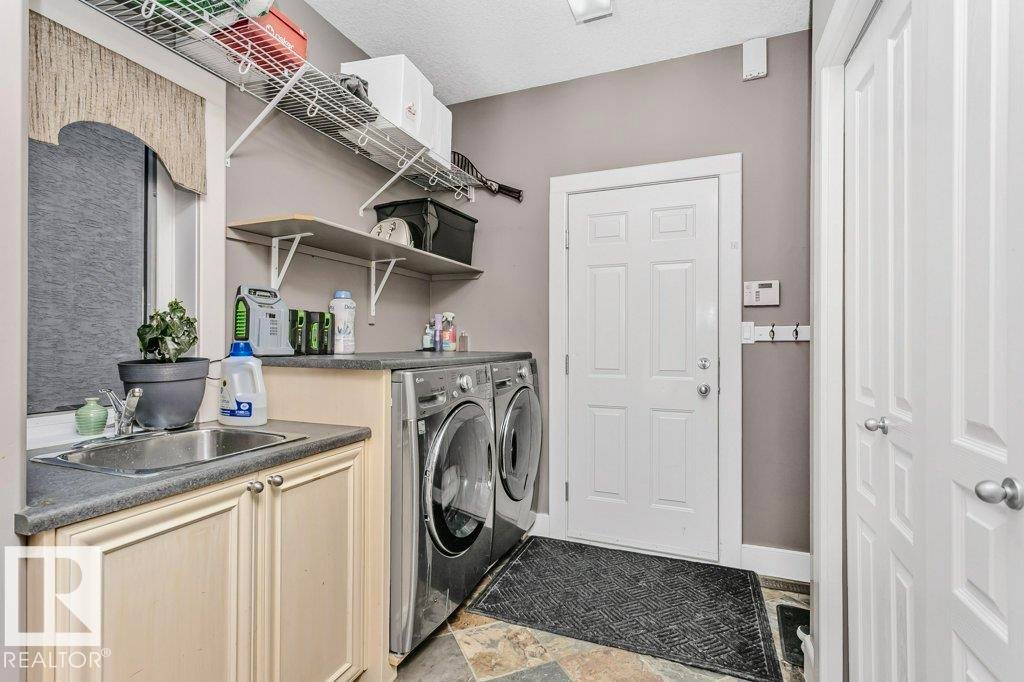 Laundry area with washing machine and dryer and stone finish flooring - 1579 Hector Road, Edmonton, AB - Indoor Photo Showing Laundry Room