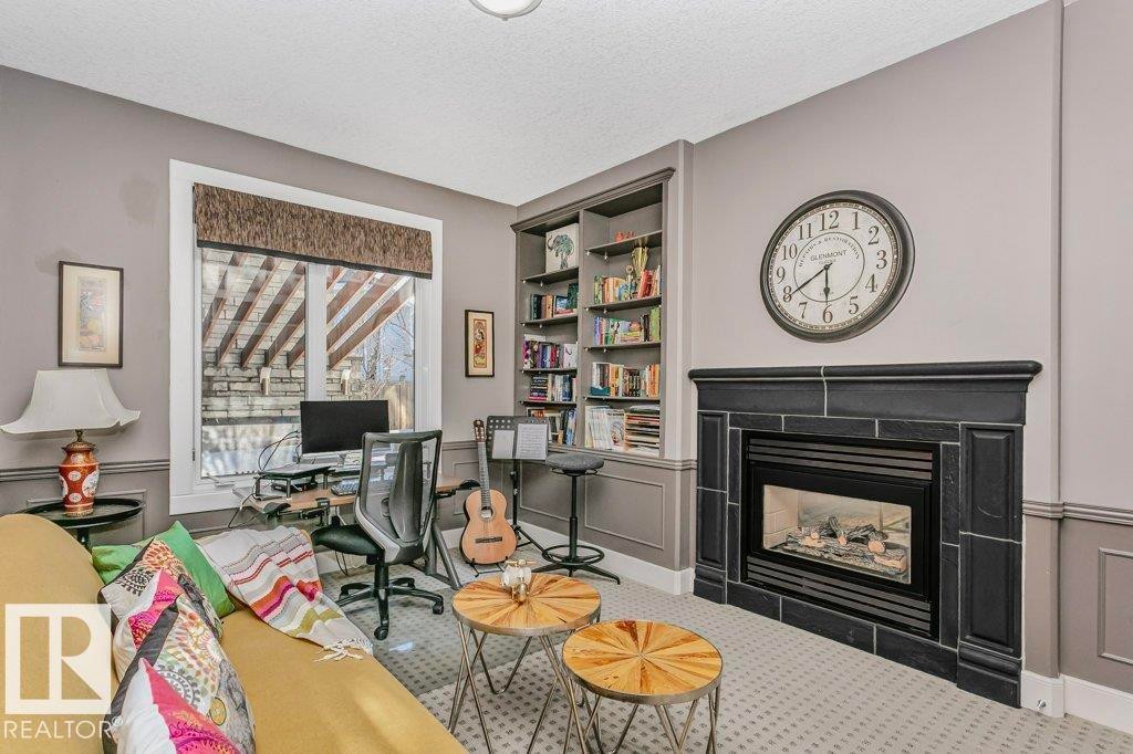 Office area with built in features, a fireplace, a textured ceiling, carpet flooring, and wainscoting - 1579 Hector Road, Edmonton, AB - Indoor Photo Showing Living Room With Fireplace