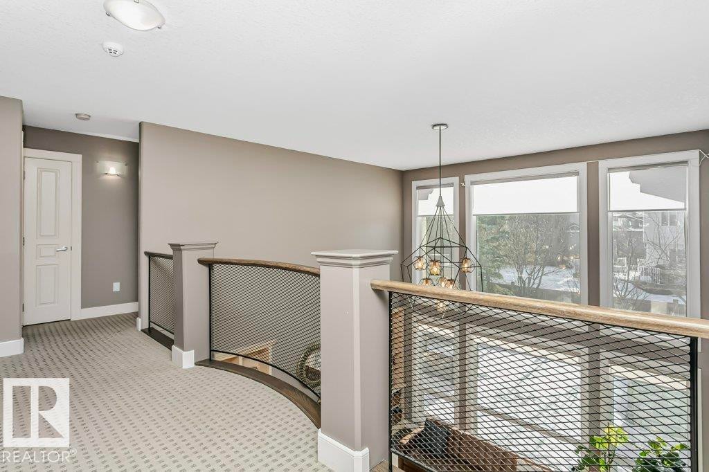 Hall featuring an upstairs landing, suspended lighting, and light colored carpet - 1579 Hector Road, Edmonton, AB - Indoor Photo Showing Other Room