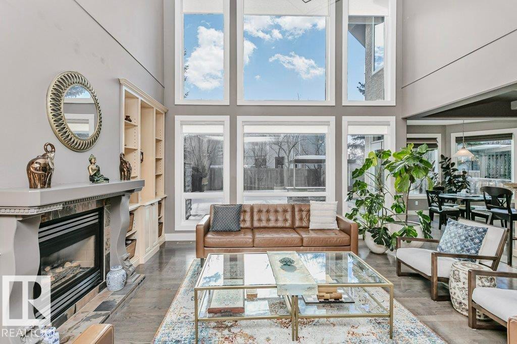 Living area with a high ceiling, a premium fireplace, built in features, and wood finished floors - 1579 Hector Road, Edmonton, AB - Indoor Photo Showing Living Room With Fireplace