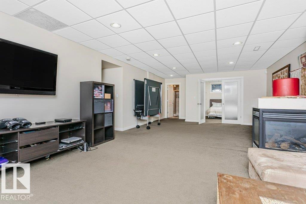 Living area with light carpet, a multi sided fireplace, recessed lighting, and a drop ceiling - 1579 Hector Road, Edmonton, AB - Indoor With Fireplace