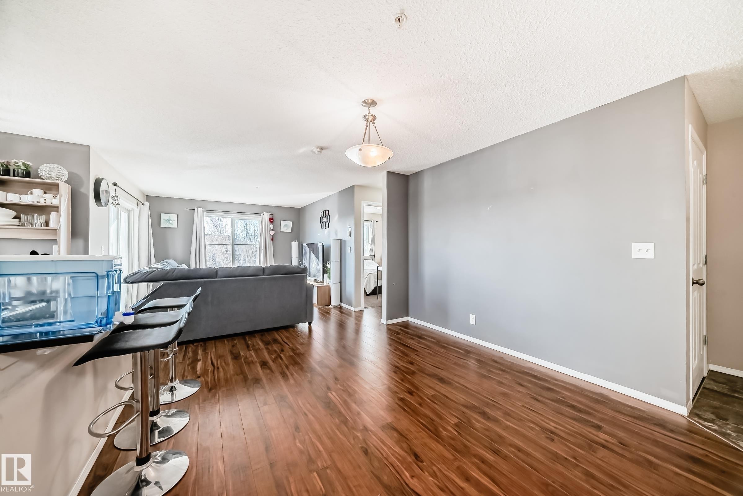 Living area with dark wood-style floors and baseboards - 302 530 Watt Boulevard Sw, Edmonton, AB - Indoor