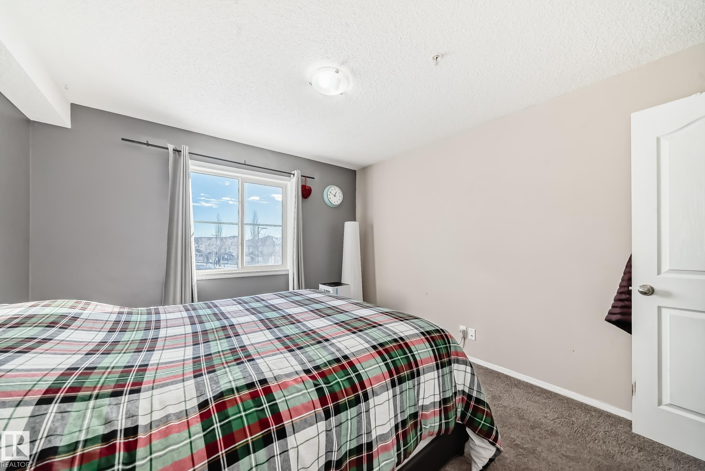 Carpeted bedroom featuring baseboards and a textured ceiling - 302 530 Watt Boulevard Sw, Edmonton, AB - Indoor Photo Showing Bedroom