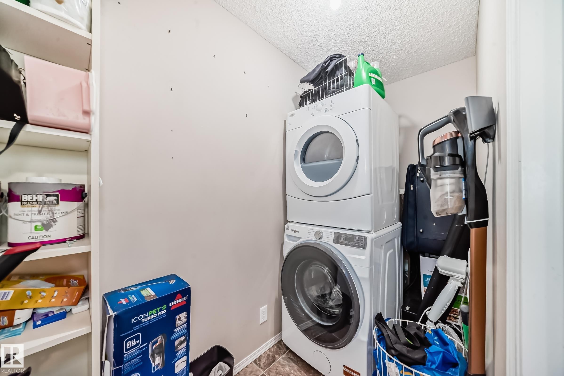 Laundry area featuring stacked washer / dryer and a textured ceiling - 302 530 Watt Boulevard Sw, Edmonton, AB - Indoor Photo Showing Laundry Room