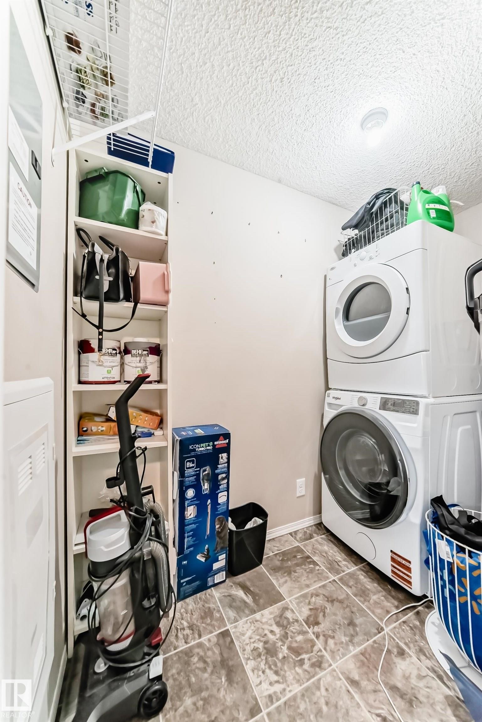 Laundry room featuring stacked washer / drying machine and a textured ceiling - 302 530 Watt Boulevard Sw, Edmonton, AB - Indoor Photo Showing Laundry Room