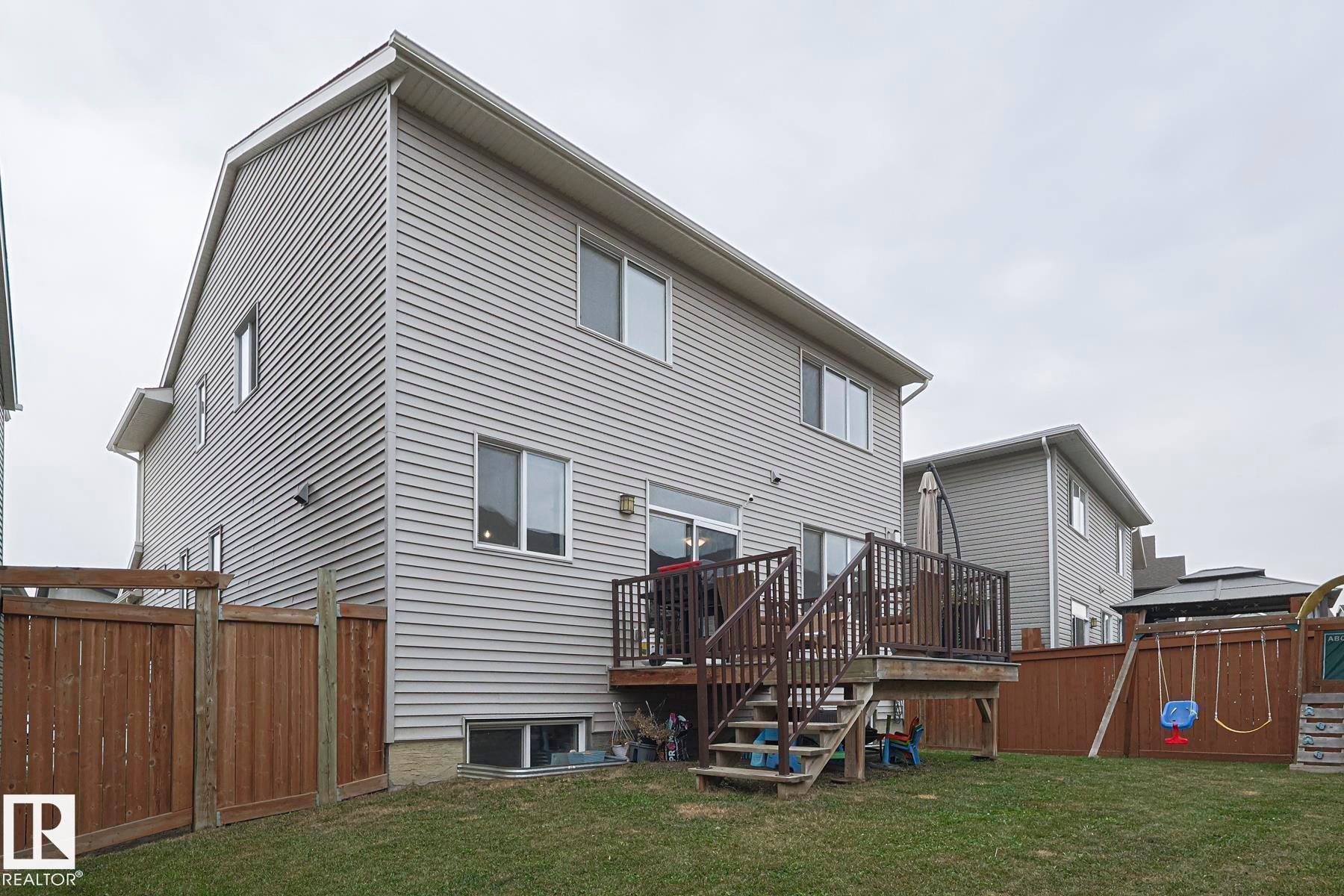 Back of property with a fenced backyard, a deck, and a playground - 2011 201 Street, Edmonton, AB - Outdoor With Deck Patio Veranda