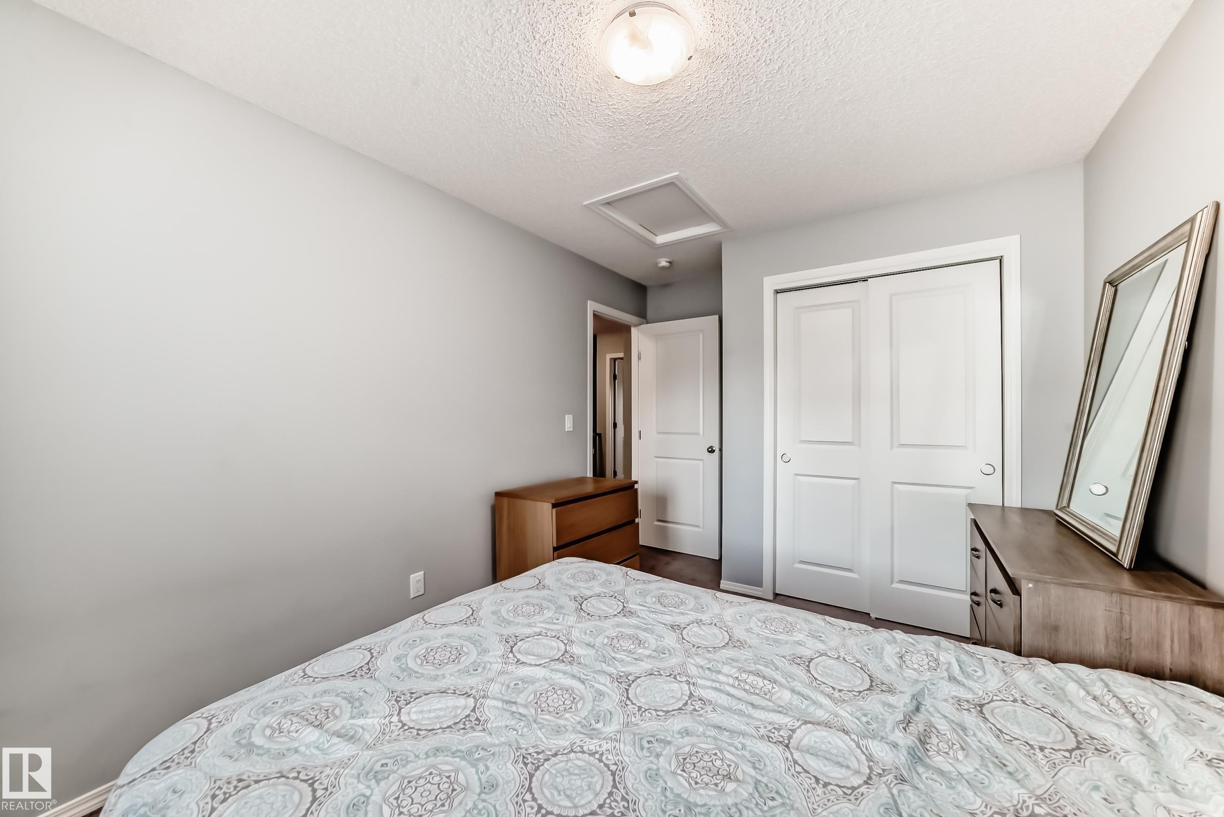 Bedroom with attic access, a textured ceiling, and a closet - 1002 Stillwater Boulevard, Edmonton, AB - Indoor Photo Showing Bedroom