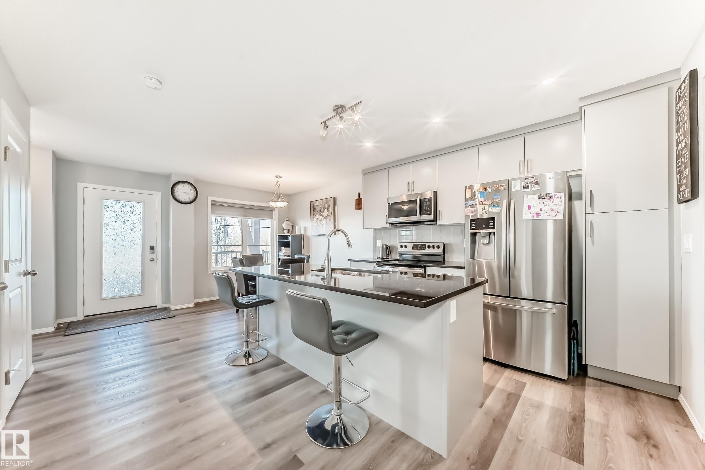 Kitchen featuring stainless steel appliances, a breakfast bar, a center island with sink, light wood finished floors, and hanging light fixtures - 1002 Stillwater Boulevard, Edmonton, AB - Indoor Photo Showing Kitchen With Upgraded Kitchen