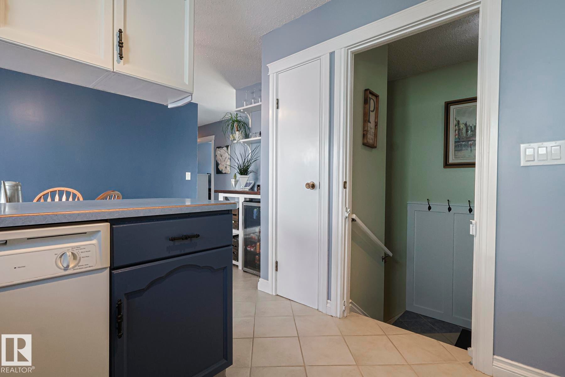 Kitchen featuring white dishwasher, a textured ceiling, light tile patterned floors, light countertops, and white cabinets - 192 Dunluce Road, Edmonton, AB - Indoor Photo Showing Other Room