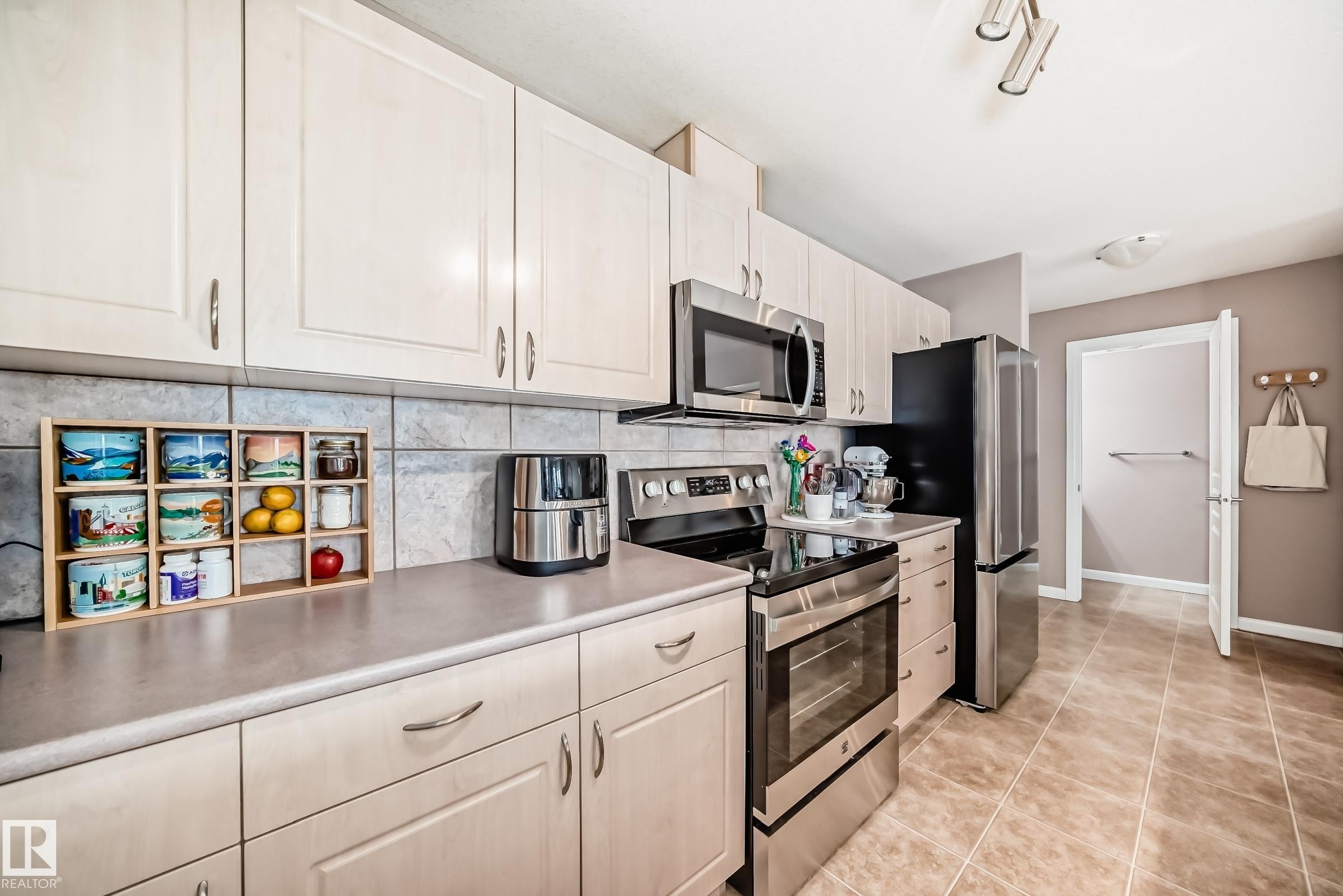 Kitchen with stainless steel appliances, light countertops, tasteful backsplash, and light tile patterned floors - 232 530 Hooke Road, Edmonton, AB - Indoor Photo Showing Kitchen With Stainless Steel Kitchen