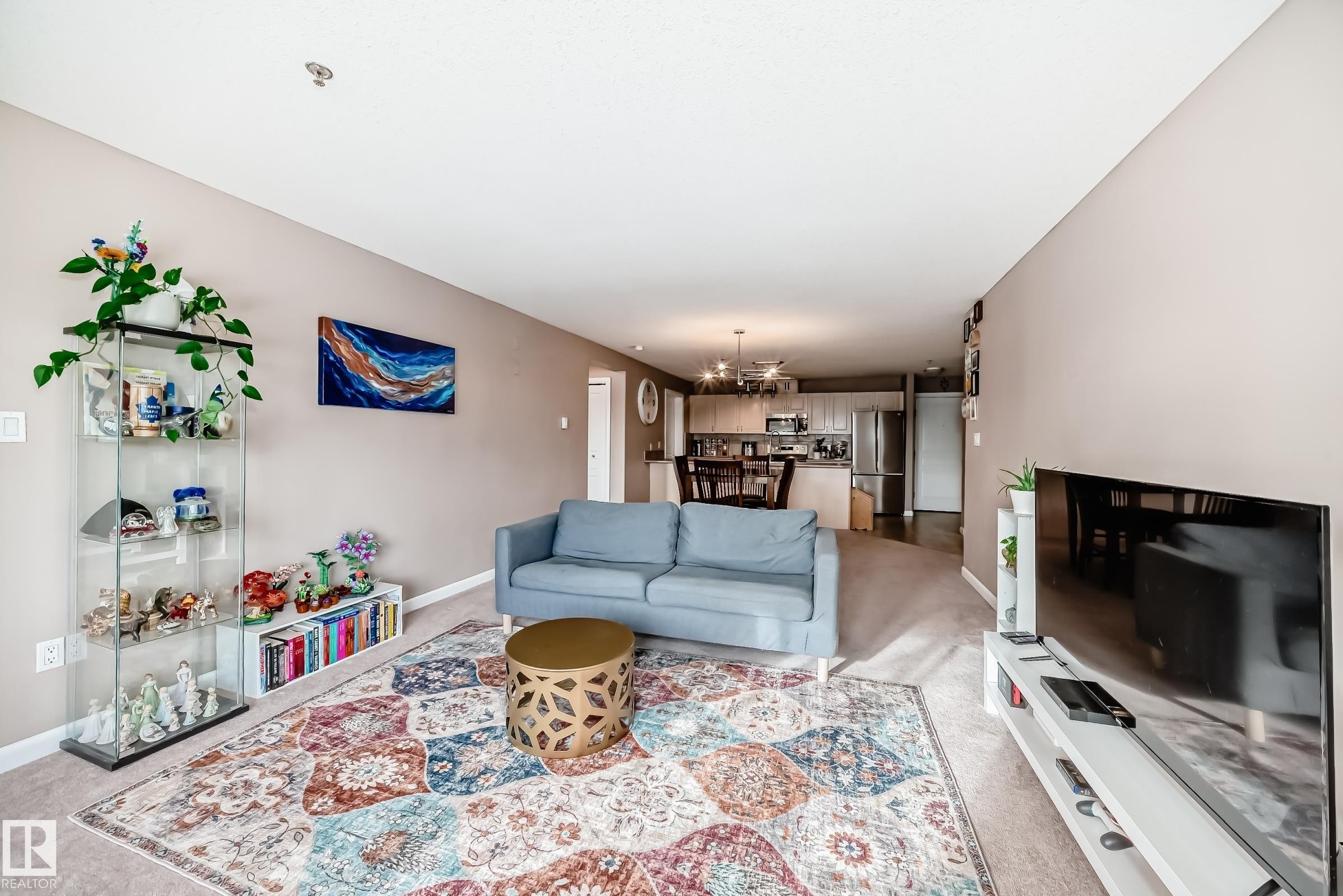 Living area featuring light colored carpet and suspended lighting - 232 530 Hooke Road, Edmonton, AB - Indoor Photo Showing Living Room