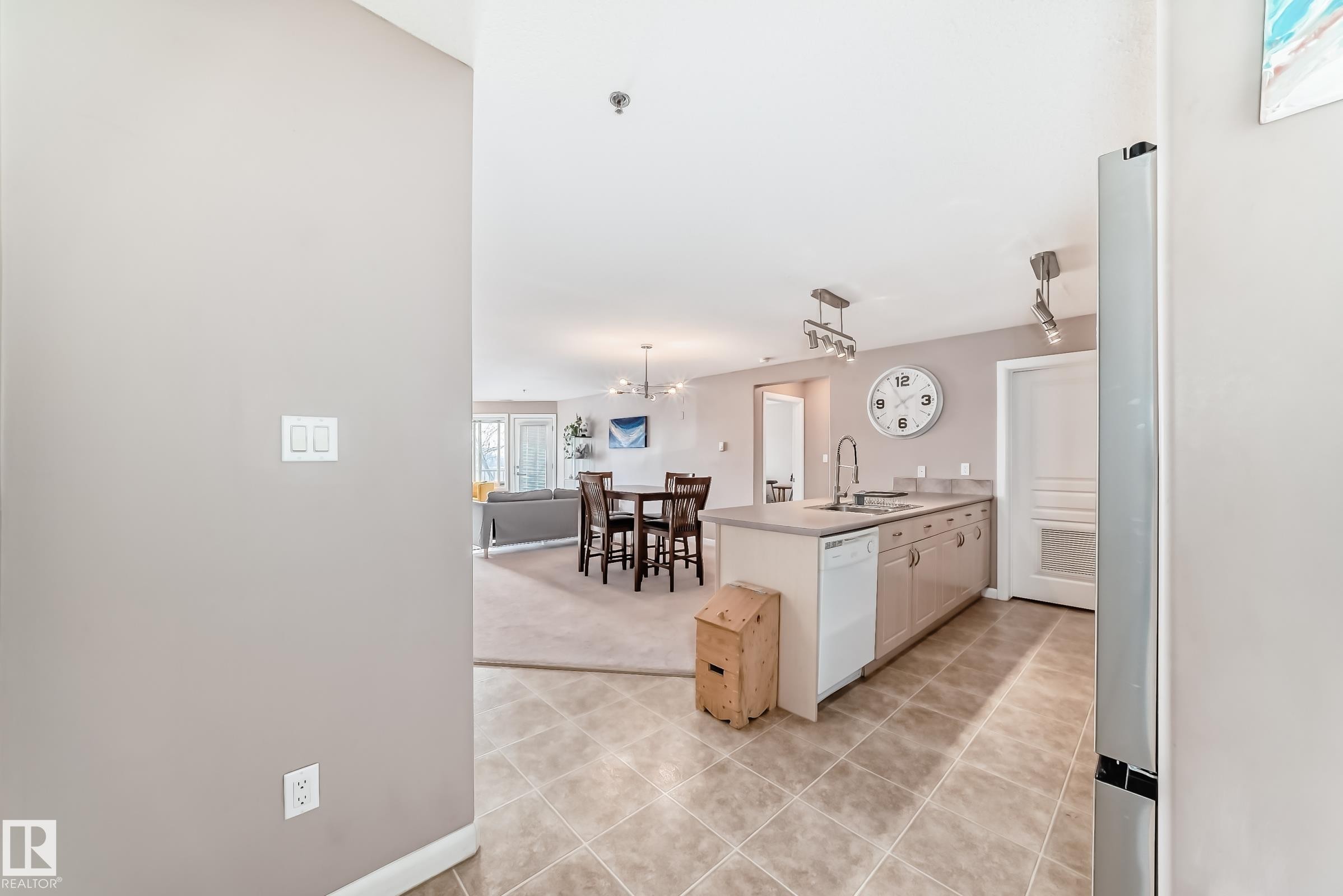 Kitchen featuring a peninsula, open floor plan, light countertops, white dishwasher, and a chandelier - 232 530 Hooke Road, Edmonton, AB - Indoor
