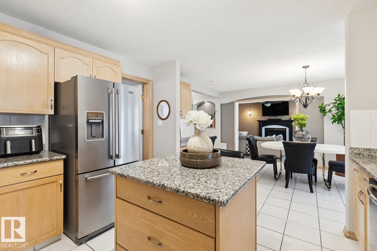 Kitchen featuring light brown cabinetry, stainless steel appliances, a kitchen island, and light stone counters - 8617 158A Avenue, Edmonton, AB - Indoor Photo Showing Kitchen