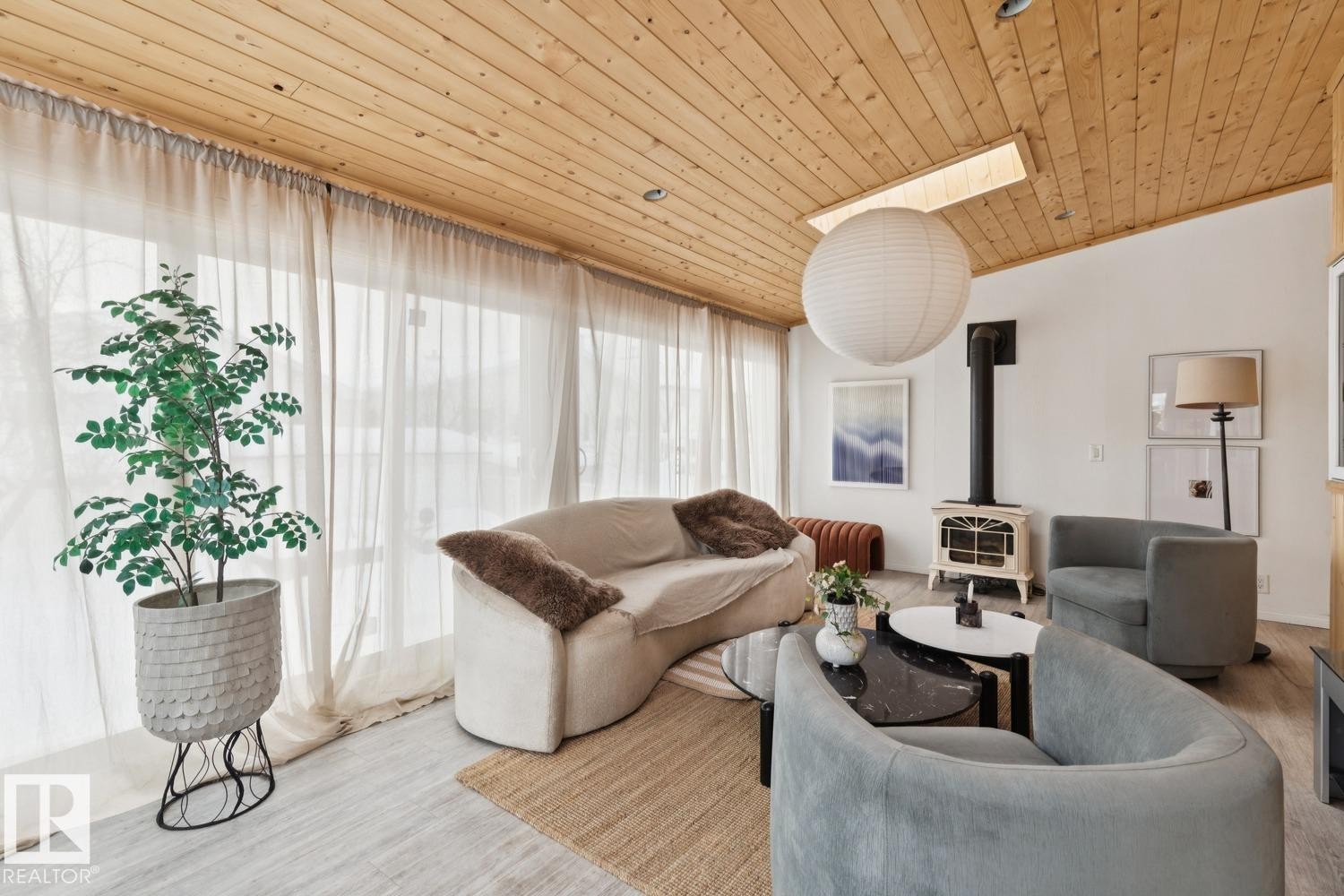 Living area featuring a wood stove, wood ceiling, and wood finished floors - 8617 158A Avenue, Edmonton, AB - Indoor