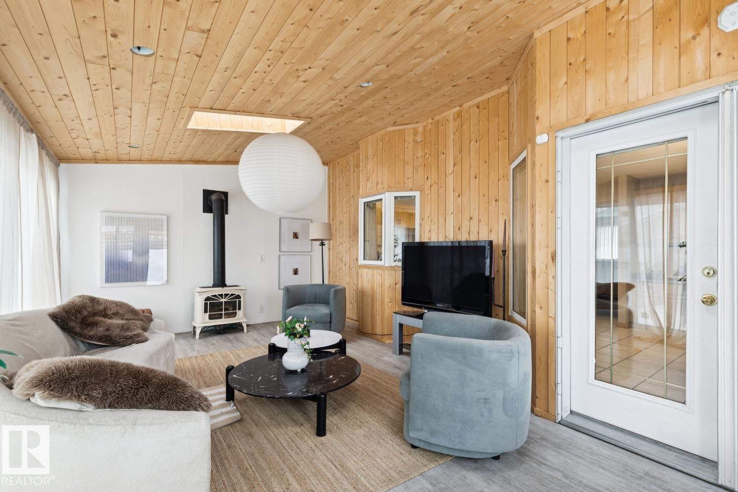 Living room with lofted ceiling, a wood stove, wooden walls, wood finished floors, and wood ceiling - 8617 158A Avenue, Edmonton, AB - Indoor Photo Showing Living Room