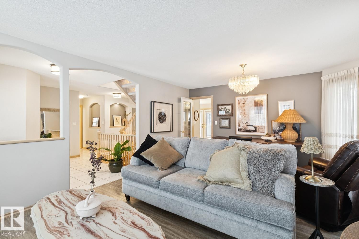 Living area featuring a chandelier, light wood finished floors, and arched walkways - 8617 158A Avenue, Edmonton, AB - Indoor Photo Showing Living Room