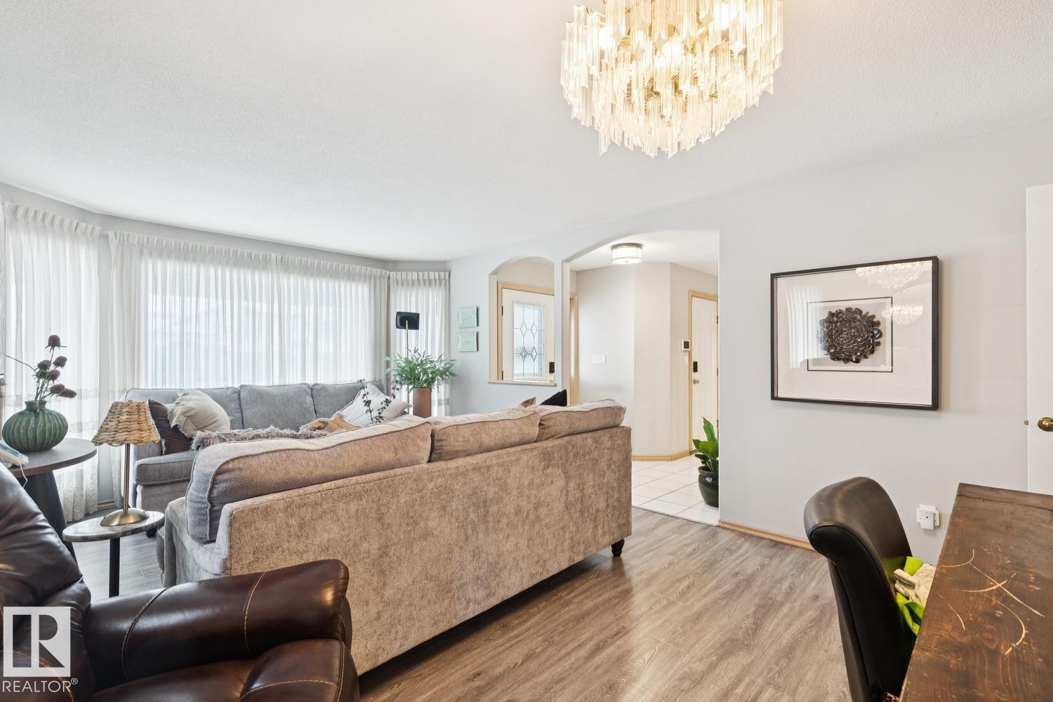 Living area with arched walkways, wood finished floors, and a chandelier - 8617 158A Avenue, Edmonton, AB - Indoor Photo Showing Living Room