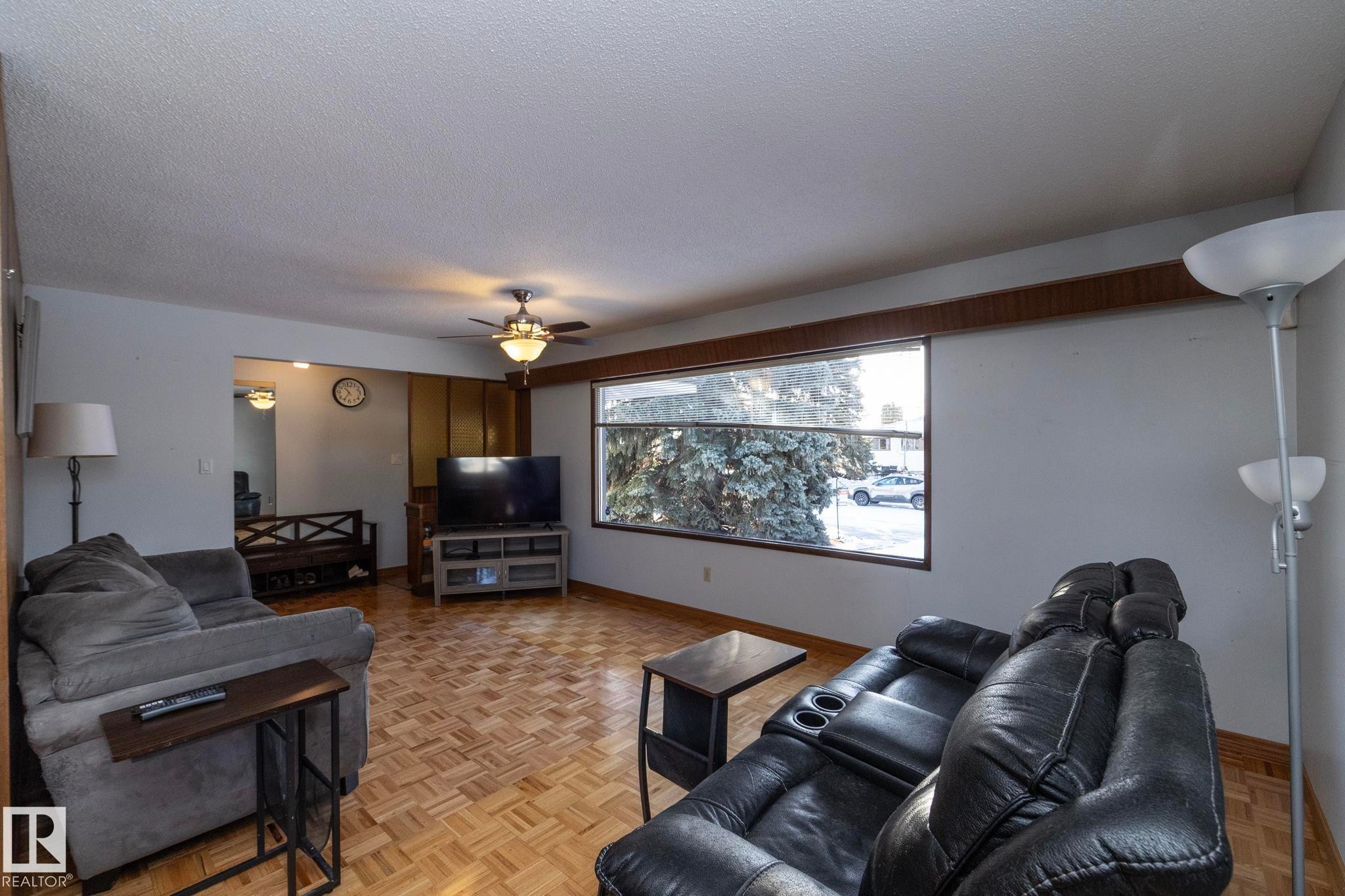 Living room featuring parquet floors, ceiling fan, and a textured ceiling - 9020 152 Avenue, Edmonton, AB - Indoor Photo Showing Living Room