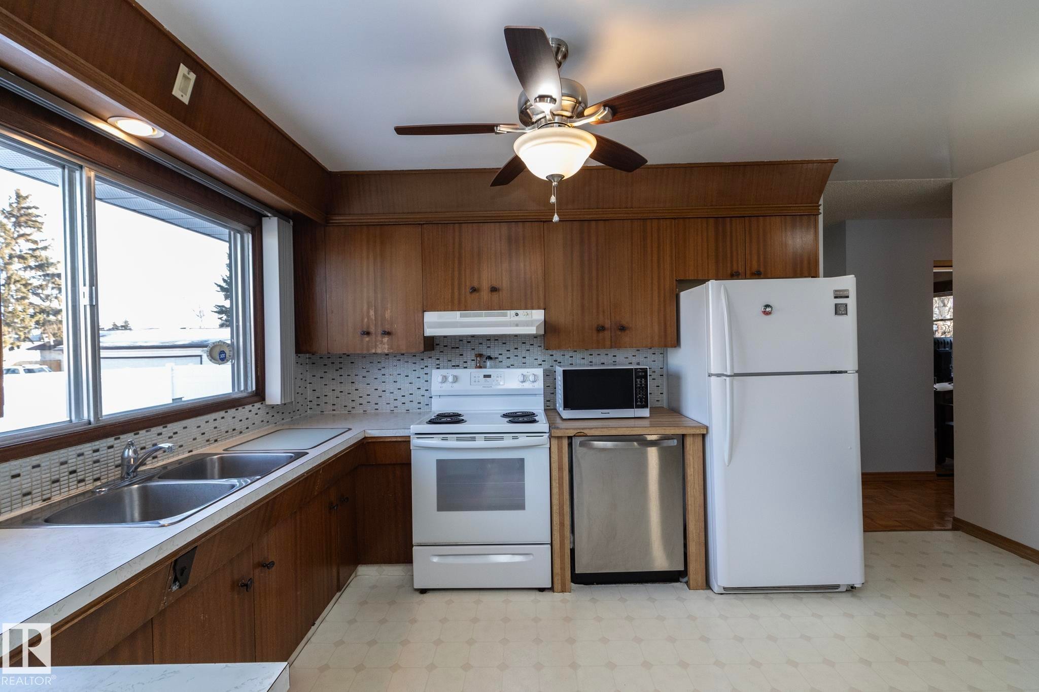 Kitchen featuring light flooring, white appliances, tasteful backsplash, a ceiling fan, and light countertops - 9020 152 Avenue, Edmonton, AB - Indoor Photo Showing Kitchen With Double Sink
