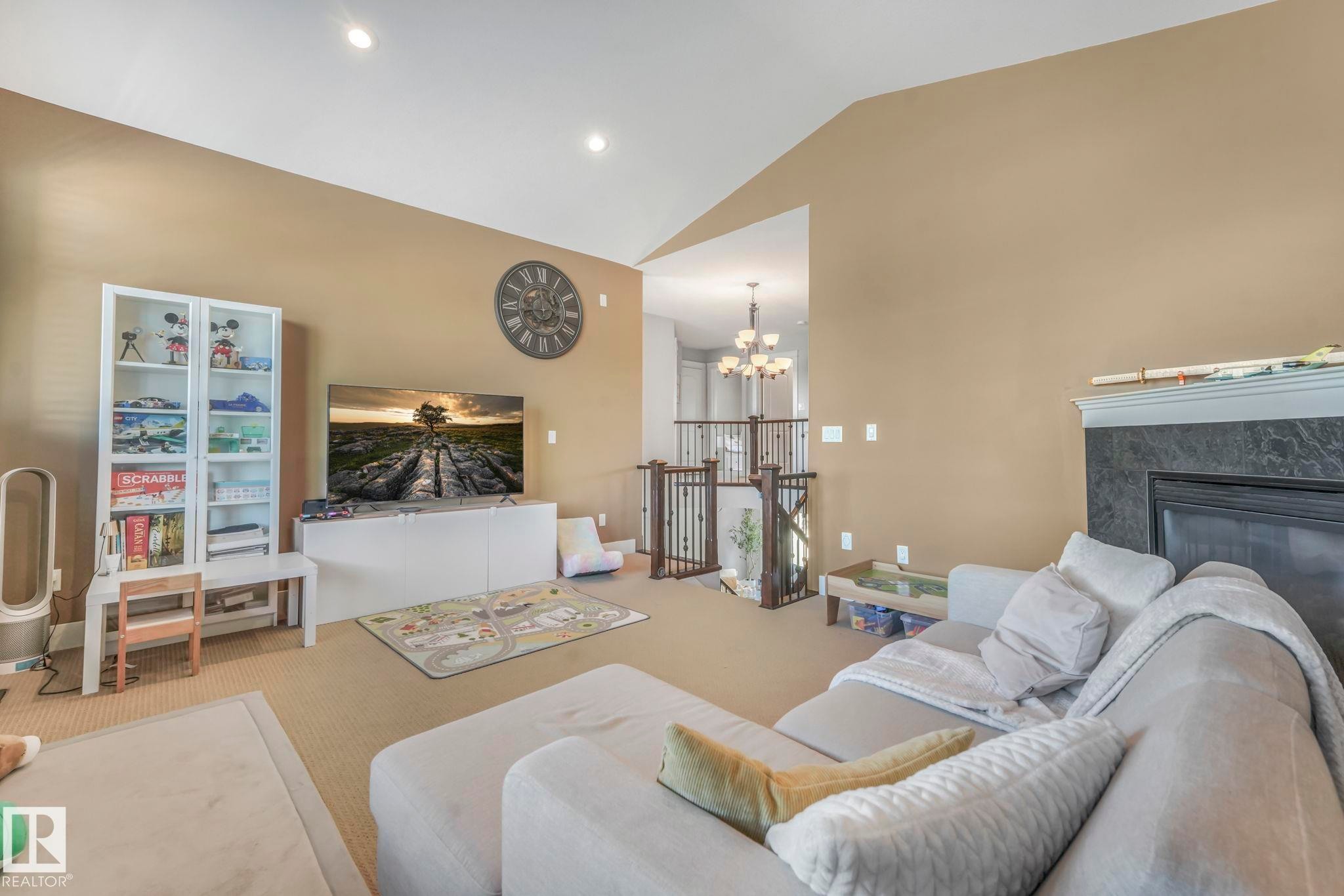 Carpeted living area featuring a chandelier, a high end fireplace, high vaulted ceiling, and recessed lighting - 2307 Rutherford Way, Edmonton, AB - Indoor Photo Showing Living Room With Fireplace