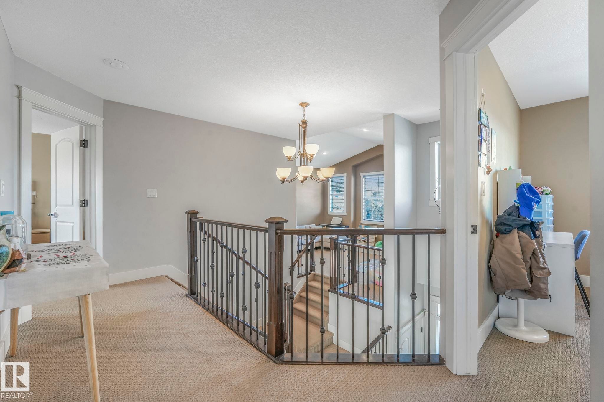 Hall featuring an upstairs landing, carpet floors, a chandelier, and vaulted ceiling - 2307 Rutherford Way, Edmonton, AB - Indoor Photo Showing Other Room
