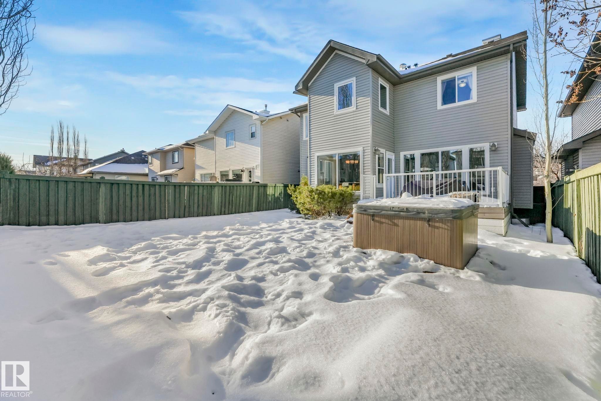 Snow covered rear of property with a hot tub, a fenced backyard, and a wooden deck - 2307 Rutherford Way, Edmonton, AB - Outdoor