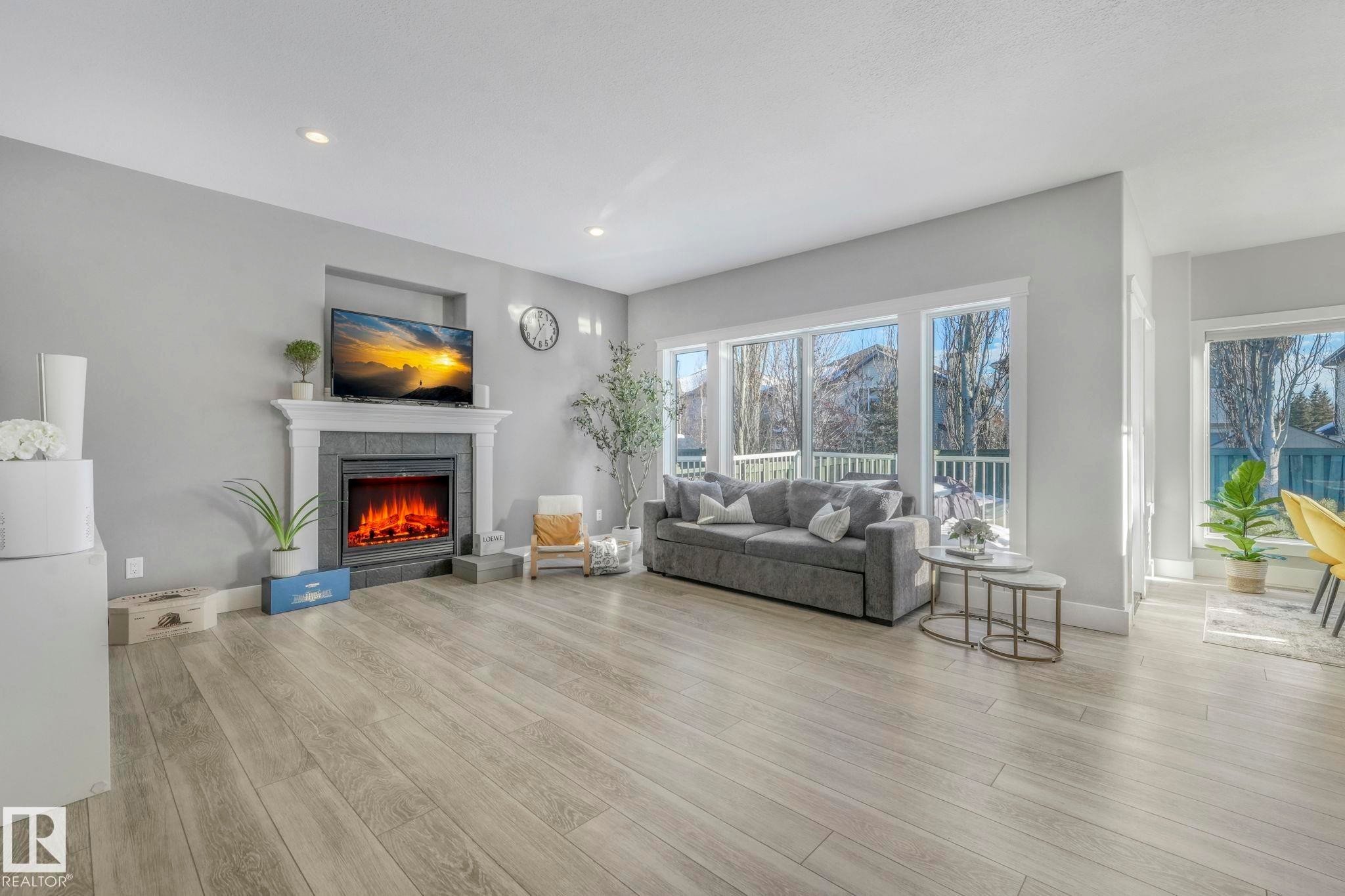 Living area with light wood-style floors, a tiled fireplace, and recessed lighting - 2307 Rutherford Way, Edmonton, AB - Indoor Photo Showing Living Room With Fireplace