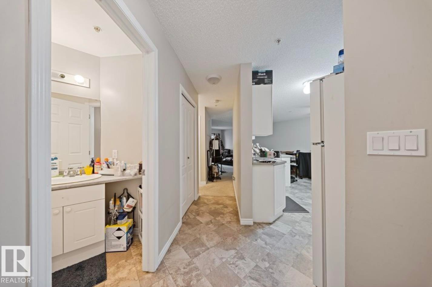 Hallway featuring a textured ceiling and a sink - 103 12110 119 Ave, Edmonton, AB - Indoor