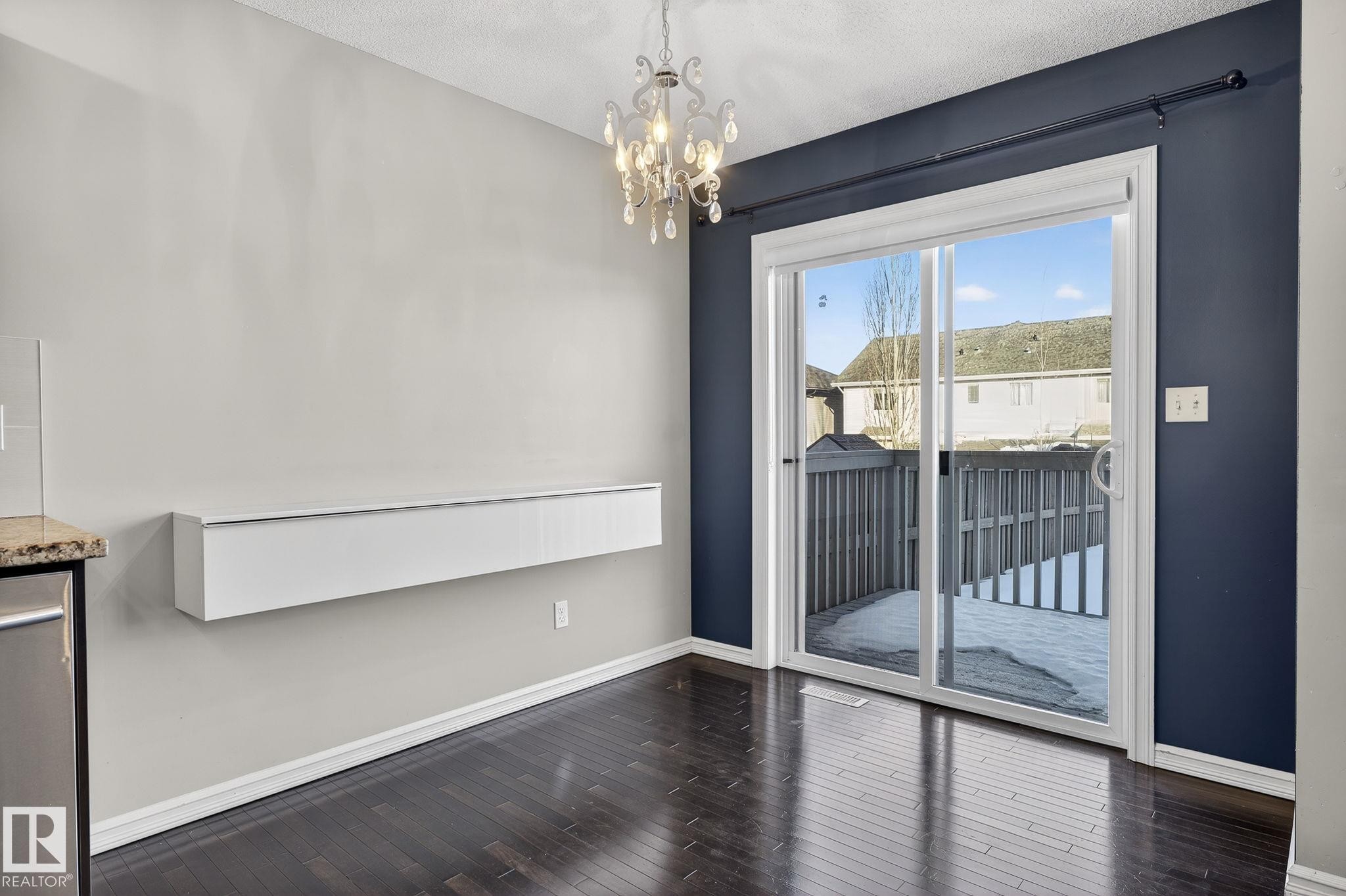 Unfurnished dining area with dark wood finished floors and suspended lighting - 2338 Casselman Crescent, Edmonton, AB - Indoor Photo Showing Other Room