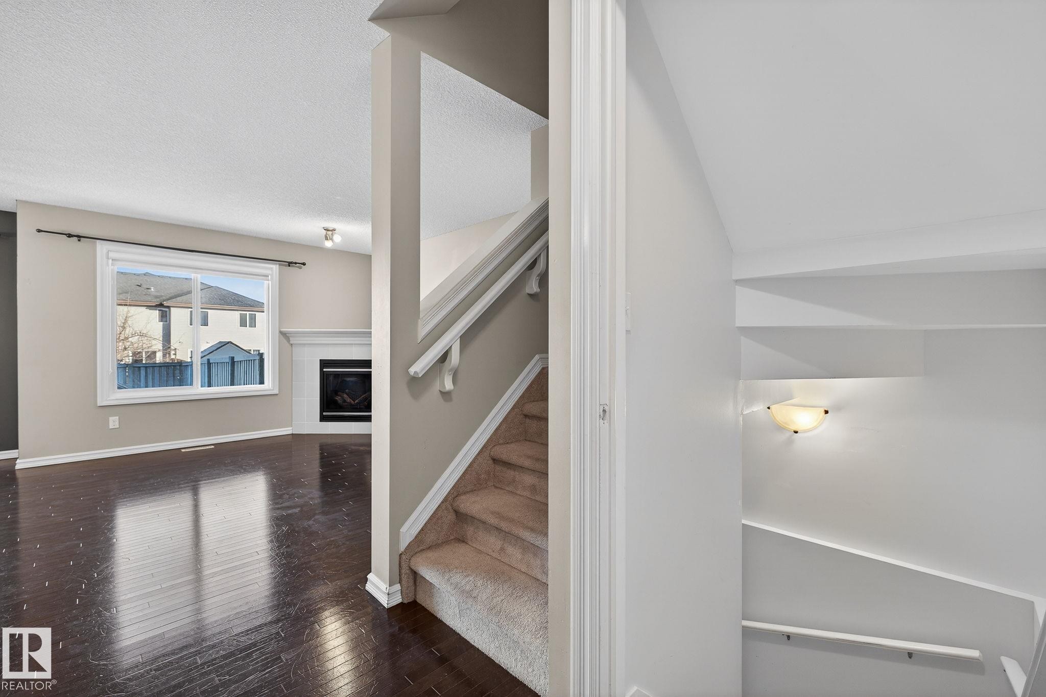 Stairway featuring a tile fireplace, hardwood / wood-style flooring, and a textured ceiling - 2338 Casselman Crescent, Edmonton, AB - Indoor Photo Showing Other Room