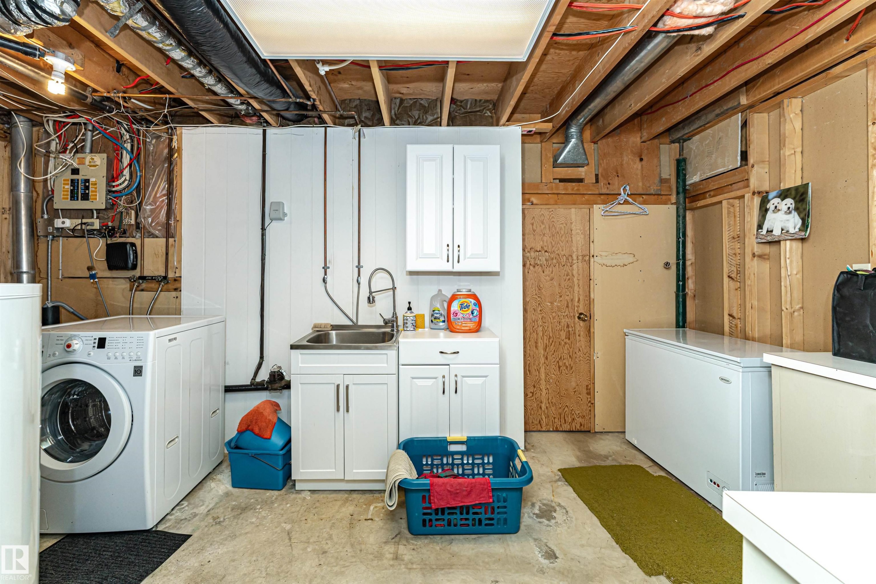 Laundry area with unfinished concrete flooring, washer / dryer, wood walls, electric panel, and cabinet space - 2112 67 Street Nw, Edmonton, AB - Indoor Photo Showing Laundry Room