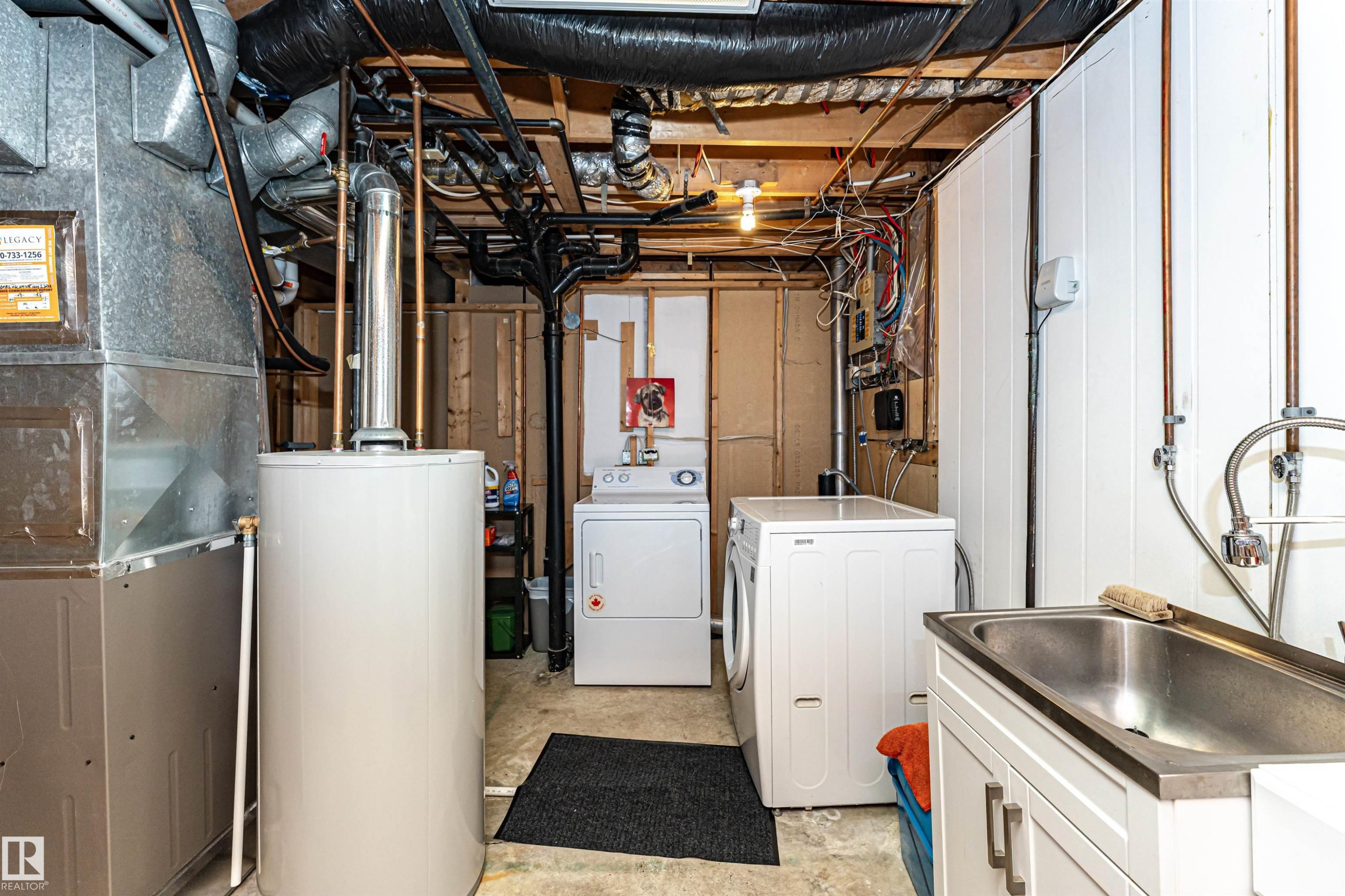 Laundry area featuring water heater, heating unit, unfinished concrete floors, and washer and dryer - 2112 67 Street Nw, Edmonton, AB - Indoor Photo Showing Laundry Room
